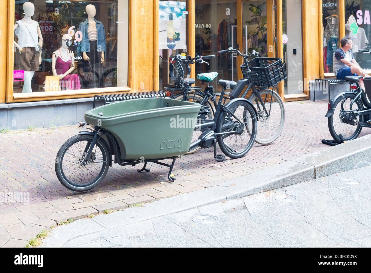 Biciclette cargo su una via dello shopping nei Paesi Bassi con vetrina del negozio Tally-Ho e scatola di carico Dolly visibile Foto Stock