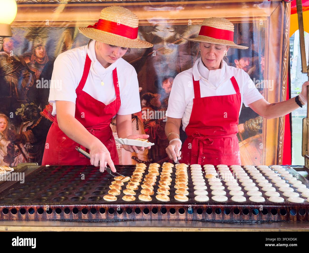 Due venditori con cappelli di paglia che preparano poffertjes a uno stand di street food olandese ad Alkmaar, Paesi Bassi & stand di poffertjes - Immagine stock catturata con smartphone