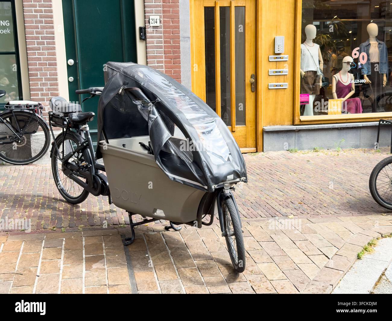 Bakfiets con copertura antipioggia trasparente su una strada olandese ad Amsterdam & nei Paesi Bassi Foto Stock