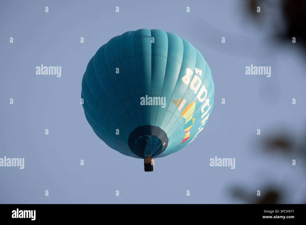 Vibrante mongolfiera turchese che vola in alto contro un cielo sereno, ideale per concetti di viaggio, avventura e libertà. Foto Stock