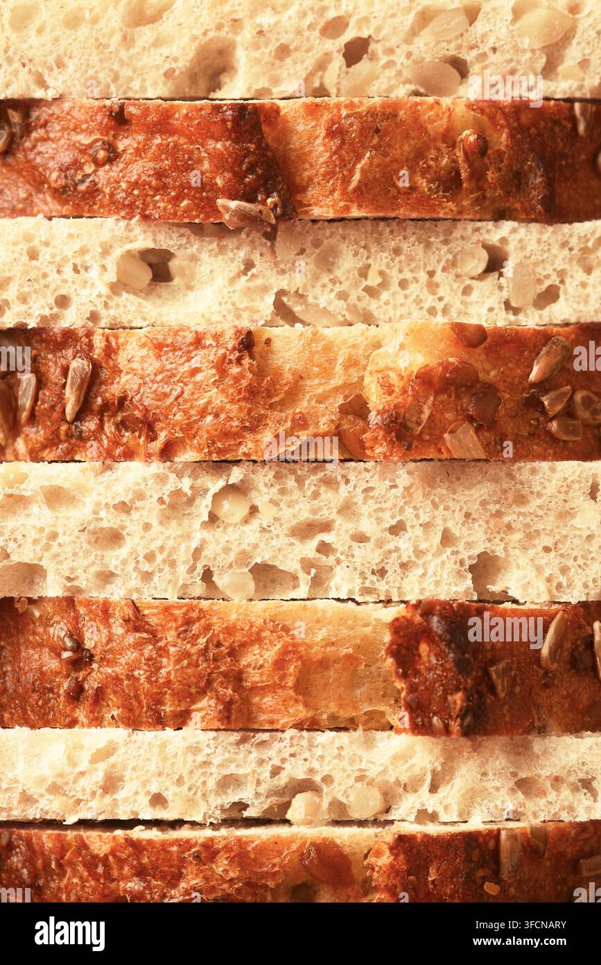 Natura morta di pane. Primo piano di fette alternate di un pane artigianale che riempiono l’inquadratura. Foto Stock
