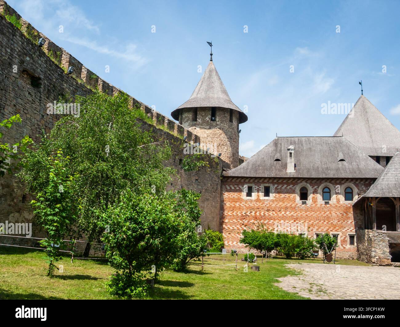 I visitatori esplorano i terreni della fortezza di Khotyn in Ucraina ammirando le sue mura di pietra e le torri sotto il cielo sereno. Foto Stock