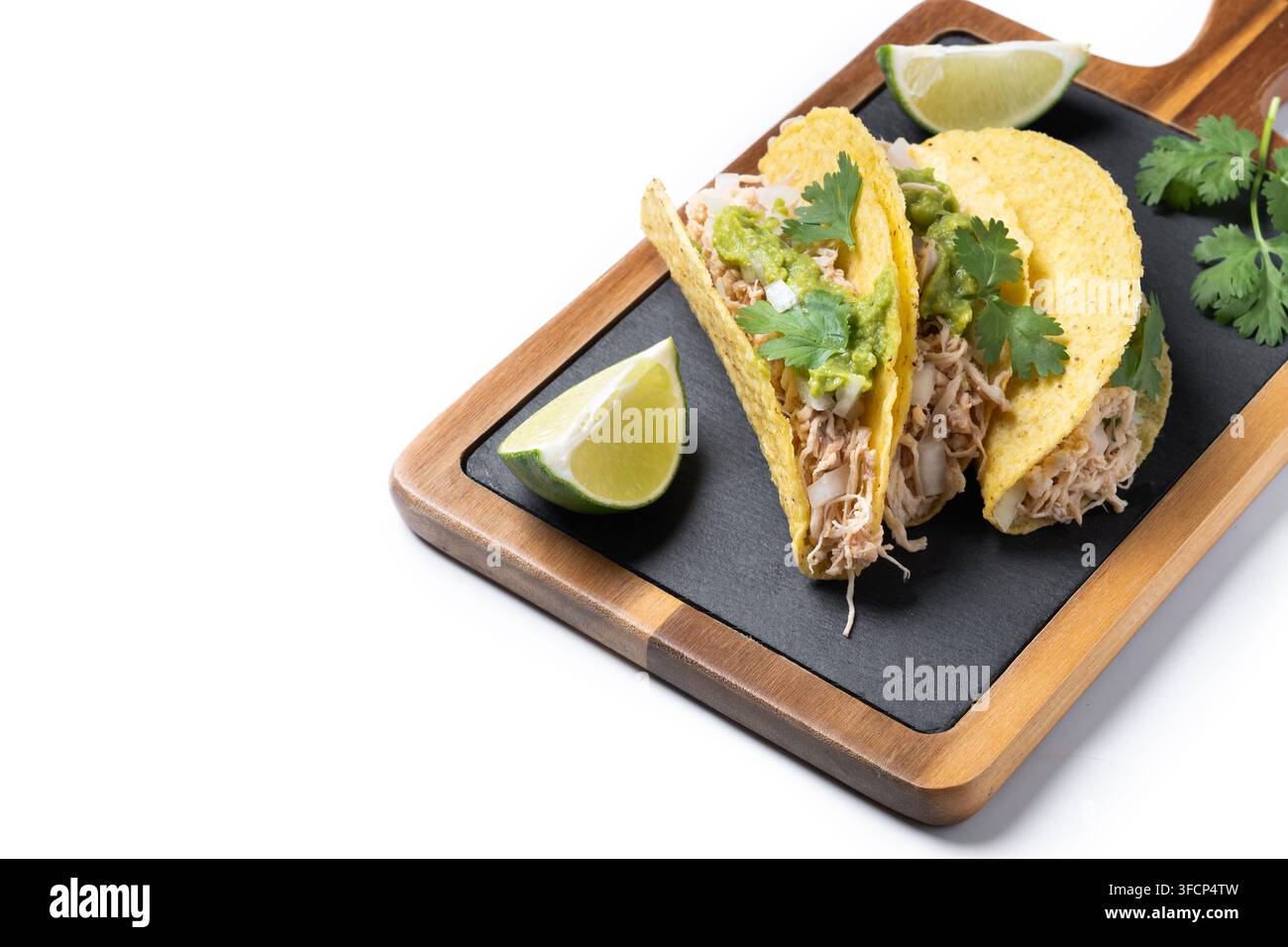 Tacos tradizionali messicani di carnitas ripieni di maiale strappato tenero, guacamole, cipolla tritata e coriandolo fresco, serviti con spicchi di lime su un legno Foto Stock