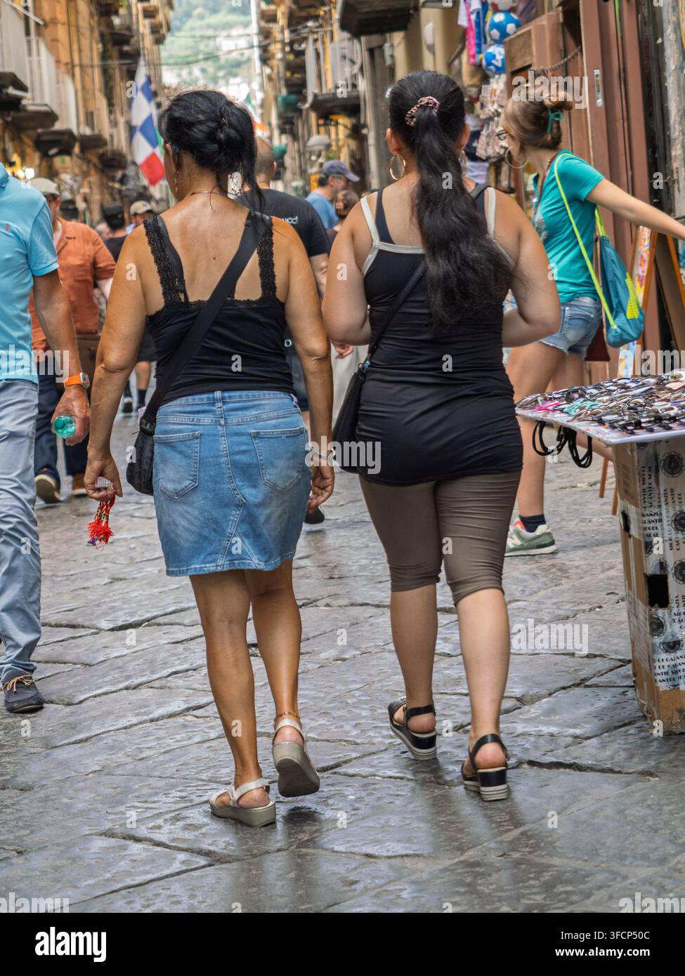 Due donne che camminano lungo un vicolo lastricato, Napoli, Italia. Foto Stock