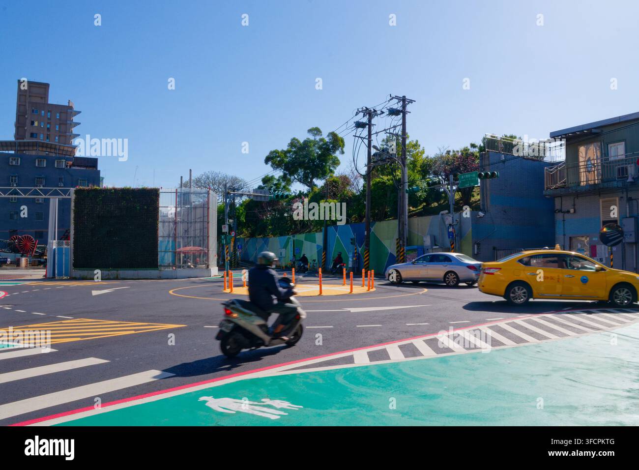 Taipei, Taiwan – 11 mar 2026: Moto e auto passano attraverso un piccolo rondò di Shilin con segnaletica sperimentale per i passaggi pedonali. Foto Stock
