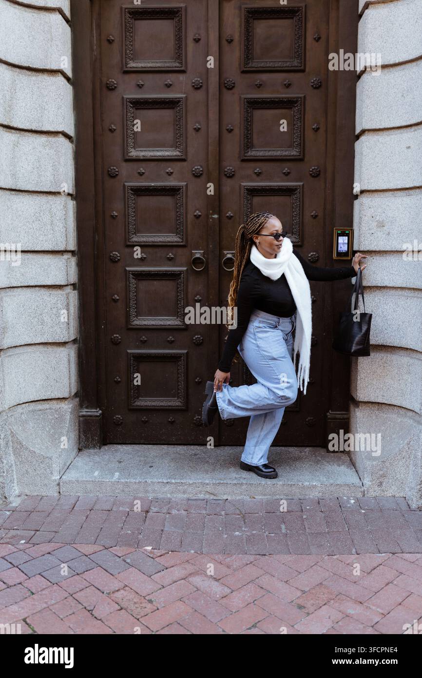 Donna elegante con trecce che utilizza un moderno sistema di ingresso tramite porta Foto Stock