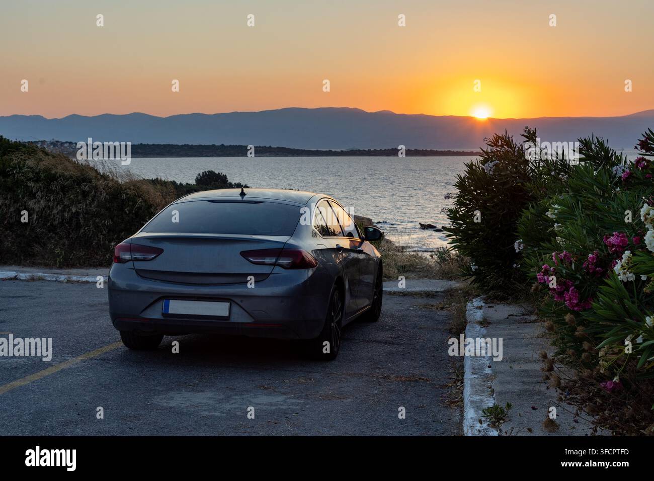 Berlina grigia parcheggiata in un punto panoramico sul tramonto costiero Foto Stock
