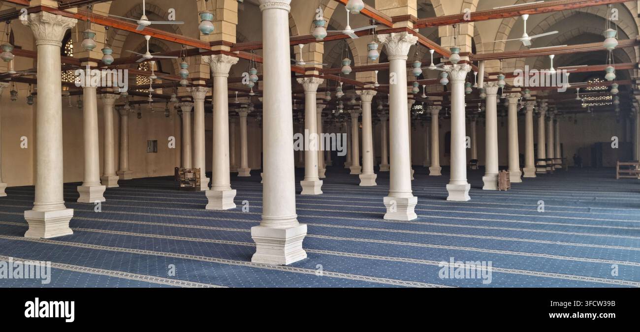 Vista dell'interno della moschea di Amr ibn al-As con file di colonne in marmo bianco, pavimento rivestito di moquette blu e lanterne sospese nel vecchio Cairo, Cairo Foto Stock