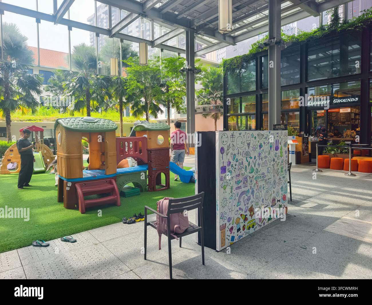 Area giochi all'aperto per bambini a Guoco Midtown a Singapore, piazza coperta con erba artificiale, un piccolo set di gioco in plastica, muro da disegno interattivo Foto Stock