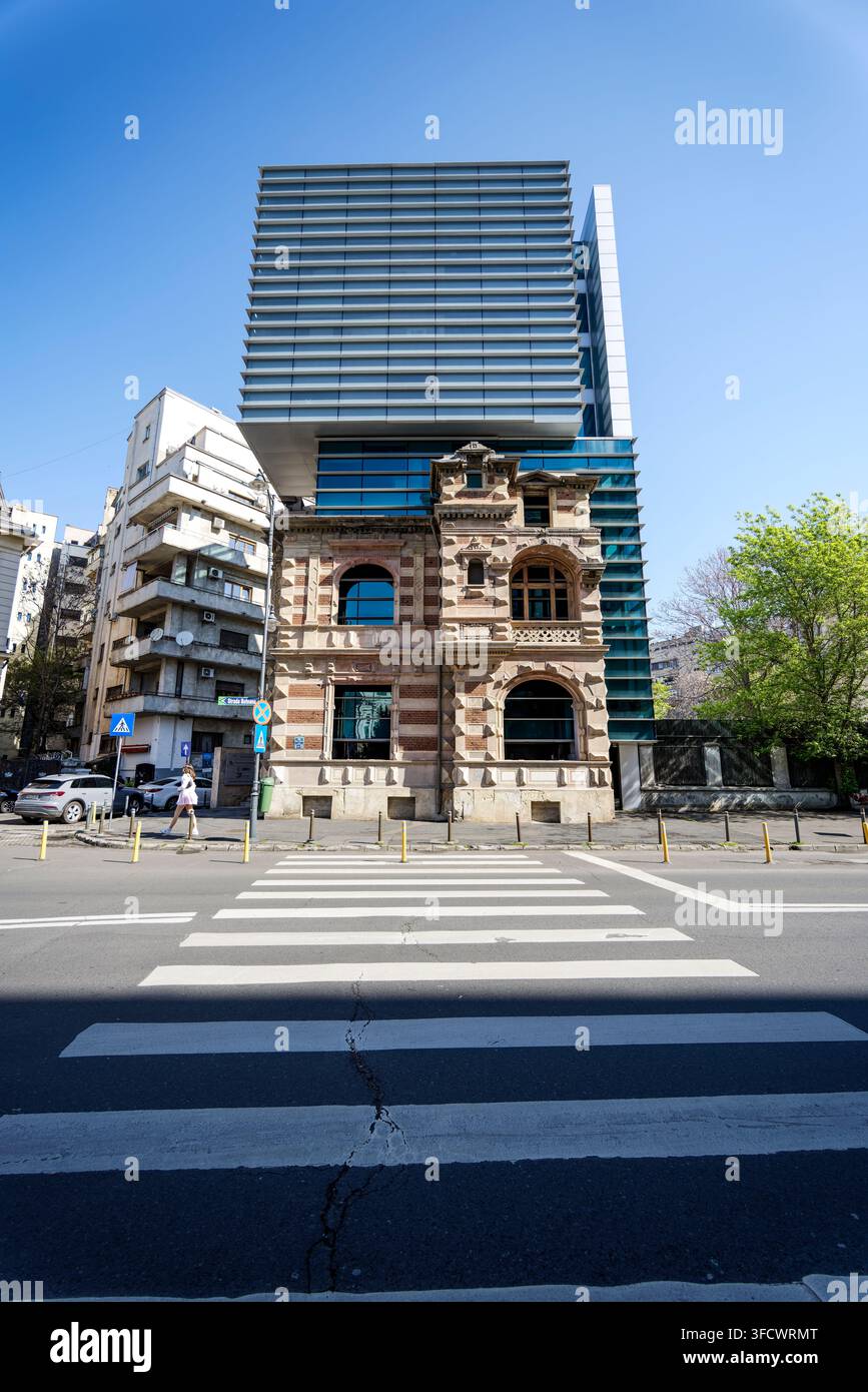Una torre in vetro/metallo direttamente sopra la casa storica Paucescu, ora sede dell'Unione degli Architetti della Romania, vicino a Piazza della Rivoluzione, Bucarest. Foto Stock