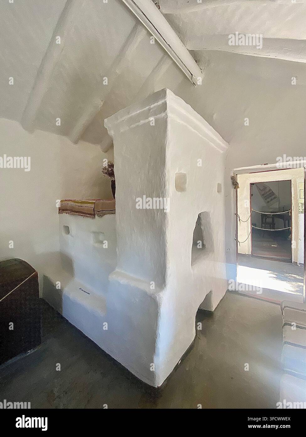 Stufa tradizionale in muratura bianca all'interno di una casa storica conservata con interno rustico - Immagine stock catturata con smartphone