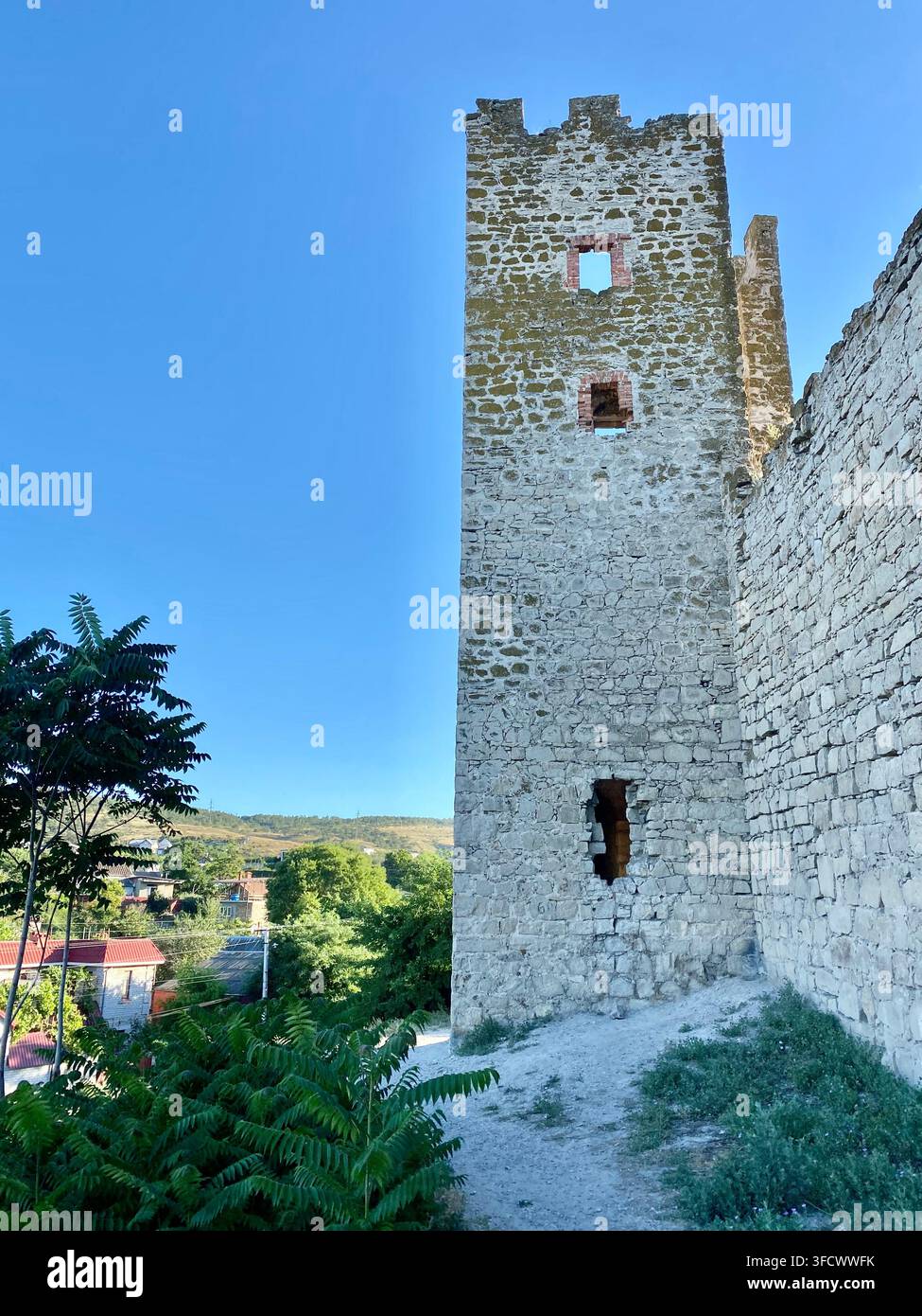 Antica torre di fortezza in pietra si erge contro il cielo azzurro estivo - Immagine stock catturata con smartphone