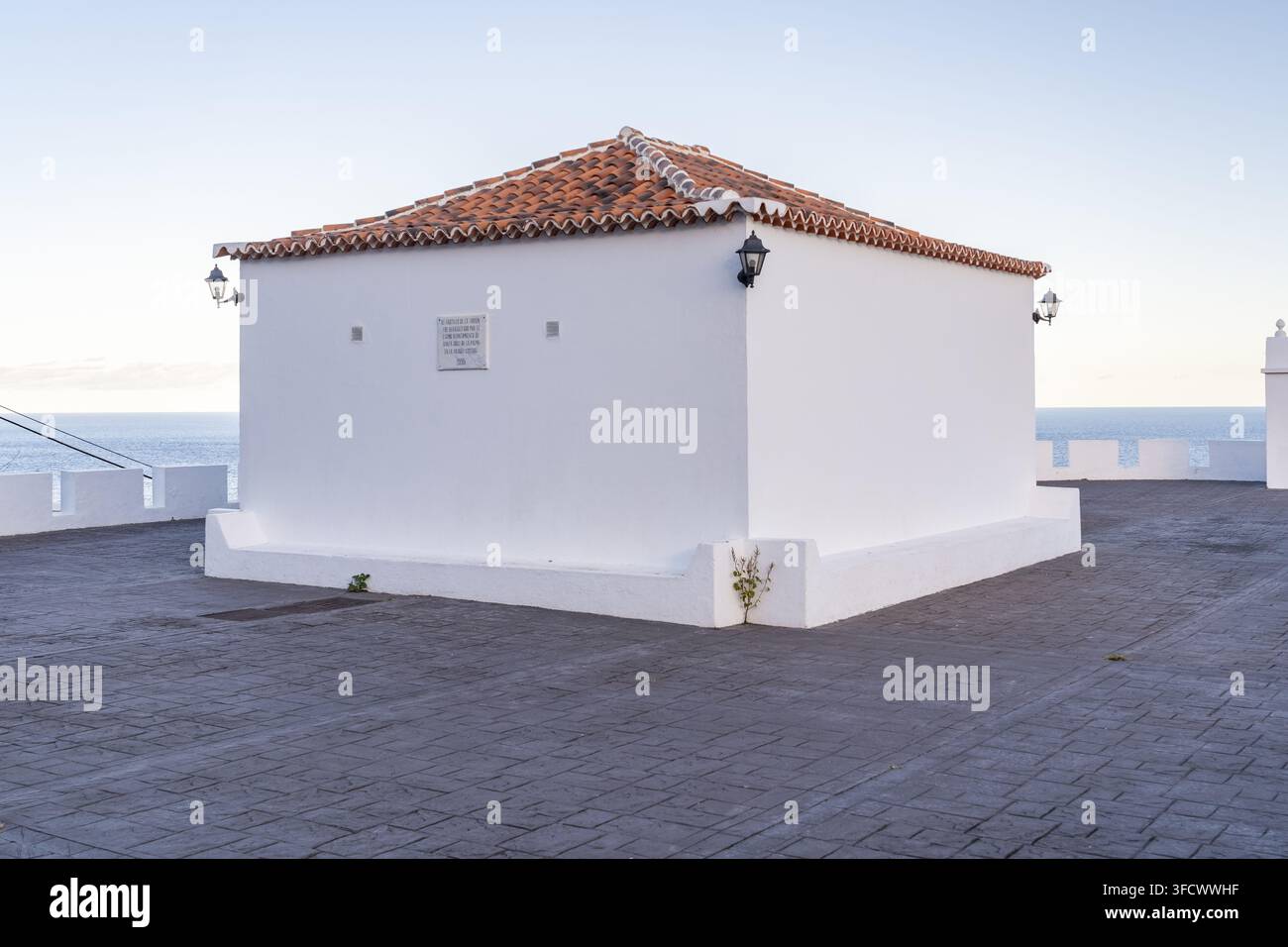 Vista dell'edificio storico di fortificazione bianca con un tetto in tegole di terracotta su una terrazza lastricata in pietra che si affaccia sul mare a Santa Cruz de La Palma Foto Stock