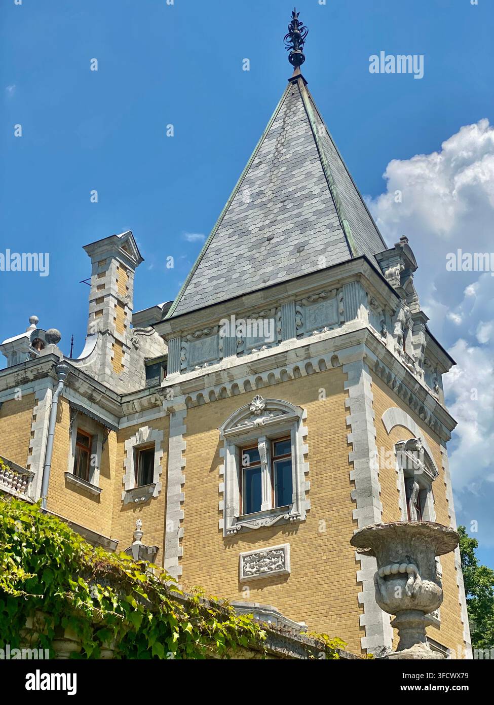 Crimea, Russia – 17 luglio 2022: Torre di palazzo ornata mostra dettagli architettonici storici sotto un cielo blu brillante - Immagine stock catturata con smartphone