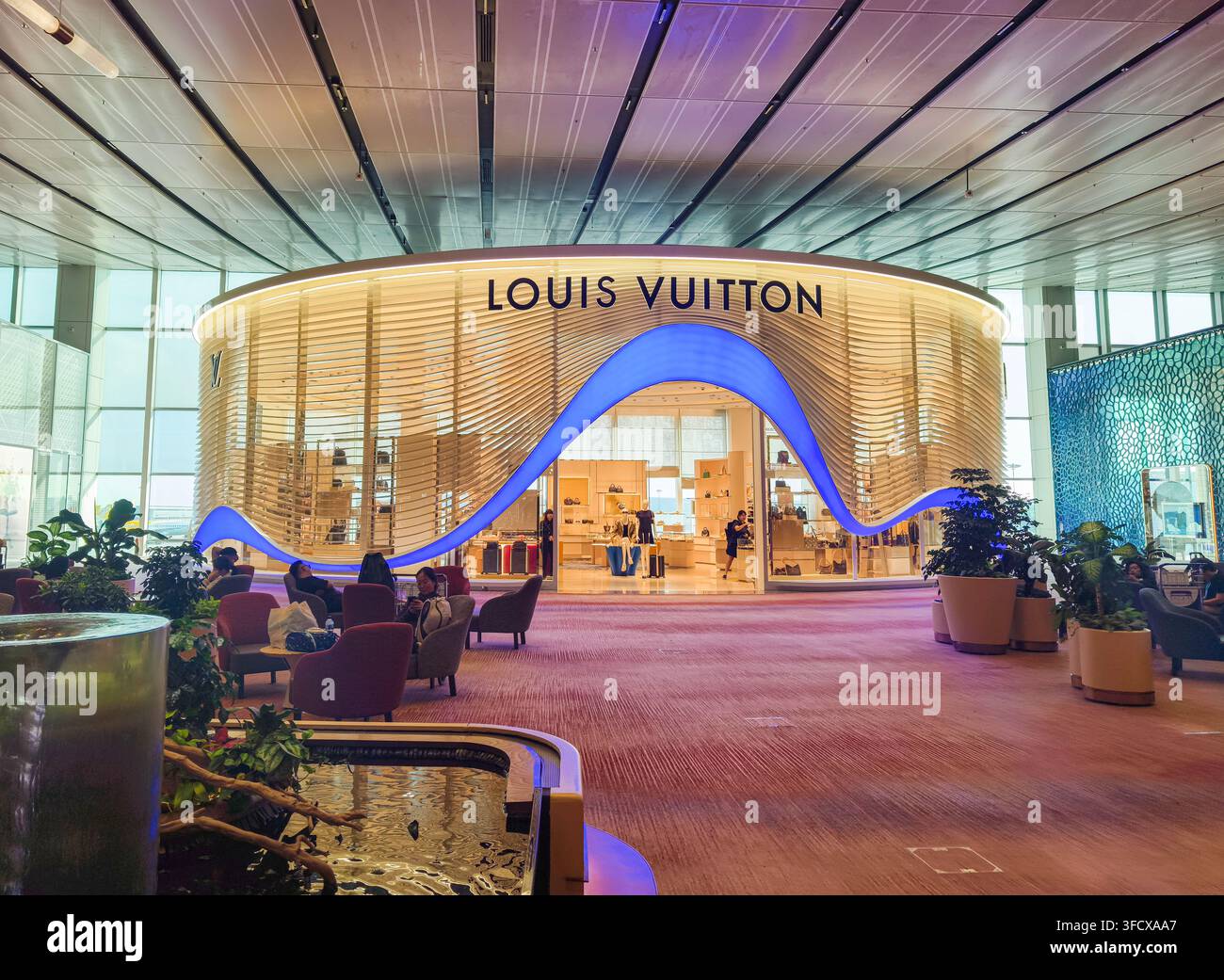 Boutique Louis Vuitton con il suo distintivo ingresso blu illuminato, curvo e a forma di onda, al Terminal 1 dell'aeroporto di Changi di Singapore Foto Stock