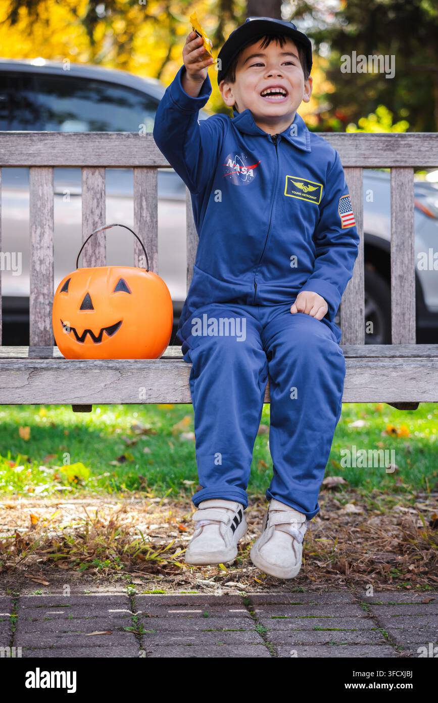 Bambino sorridente in costume da astronauta per Halloween con secchio di zucca Foto Stock