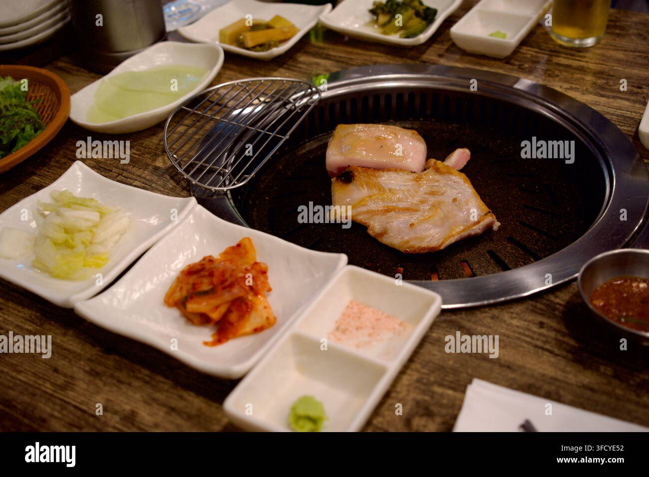 Barbecue coreano su un grill da tavolo con contorni e kimchi Foto Stock