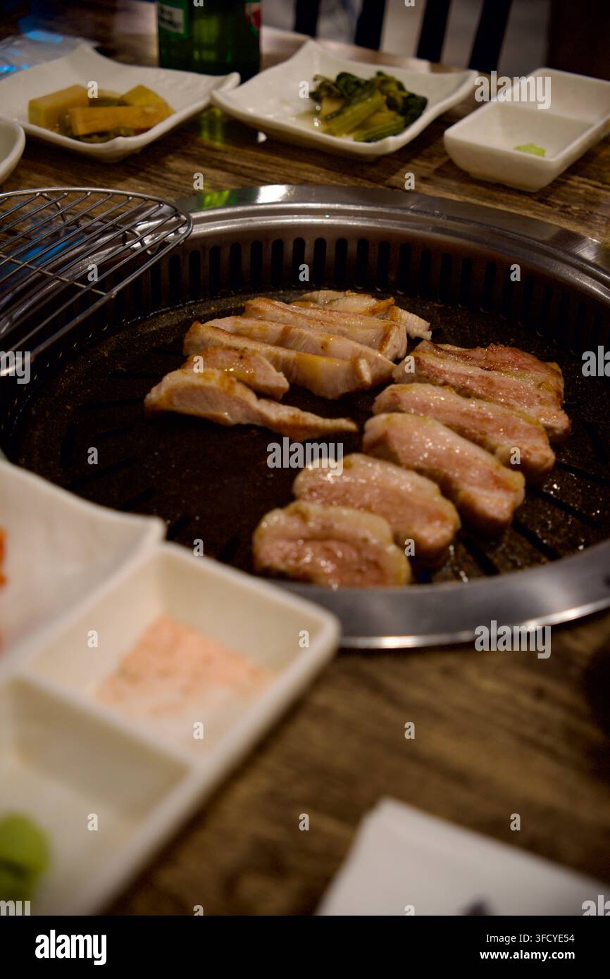 Fette di pancetta grigliate su un barbecue coreano da tavolo rotondo Foto Stock