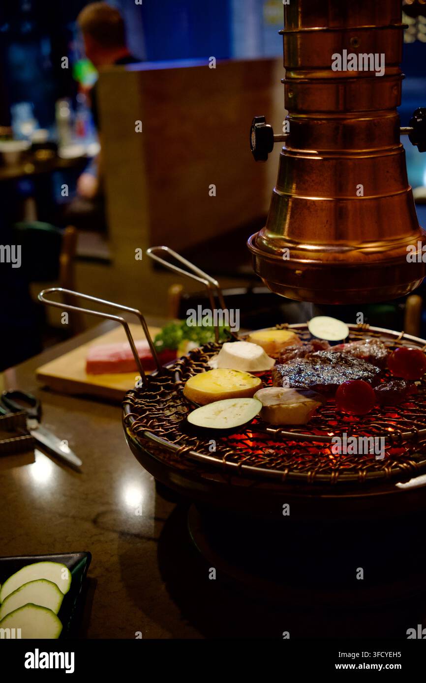 Griglie per barbecue coreane su carboni ardenti sotto una cappa extractora di rame Foto Stock