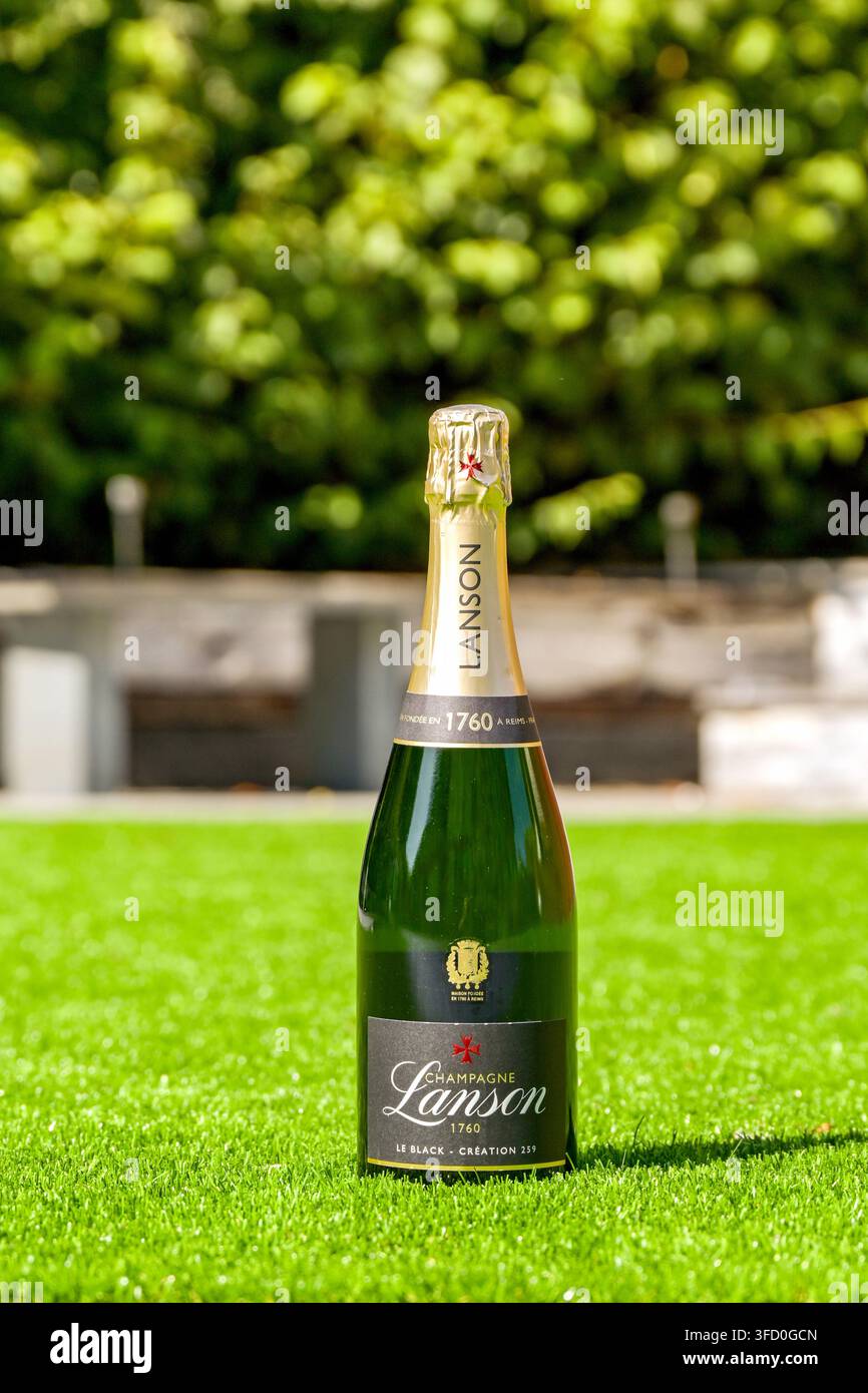 Cardiff, Galles, Regno Unito - 9 agosto 2026: Bottiglia non aperta di champagne Lanson raffreddato isolata sul rigoglioso prato del giardino posteriore di una casa Foto Stock