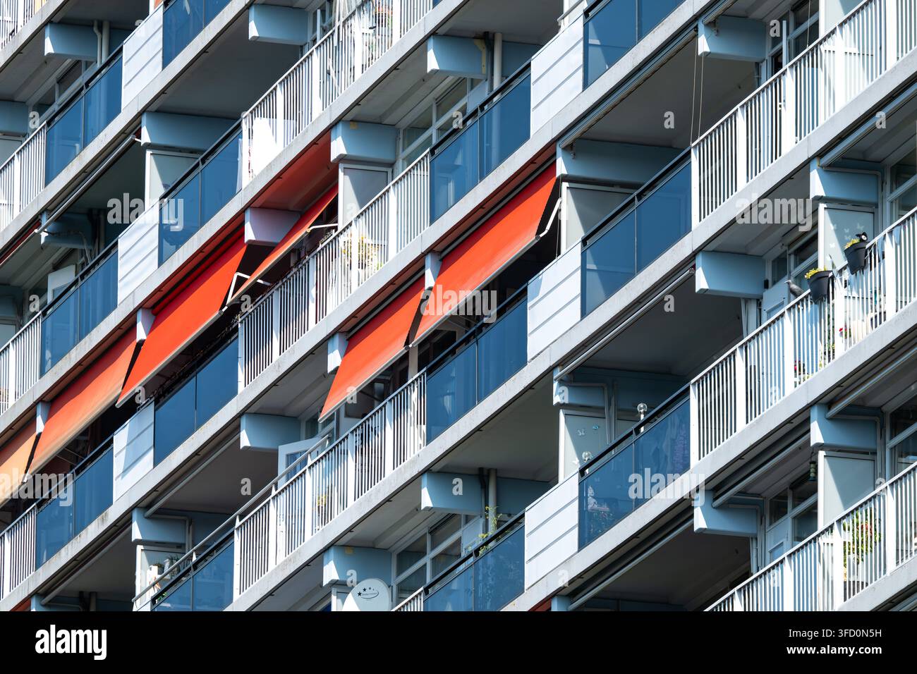 Dettaglio architettonico di edifici residenziali a Tilburg, con enfasi su file di parasole esterni arancioni contro le facciate residenziali ripetitive. Tilb Foto Stock