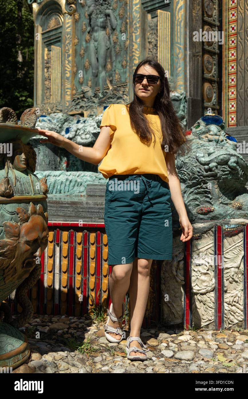 Ritratto a figura intera di una turista in piedi vicino a una fontana storica nel parco della Villa Otto Wagner. Foto Stock