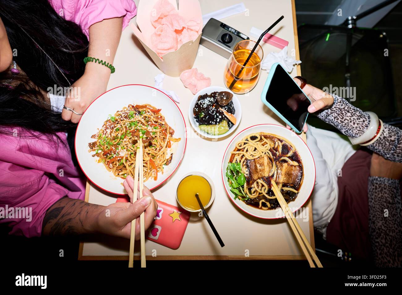 Donne asiatiche che mangiano cibo asiatico in un caffè e usano uno smartphone Foto Stock
