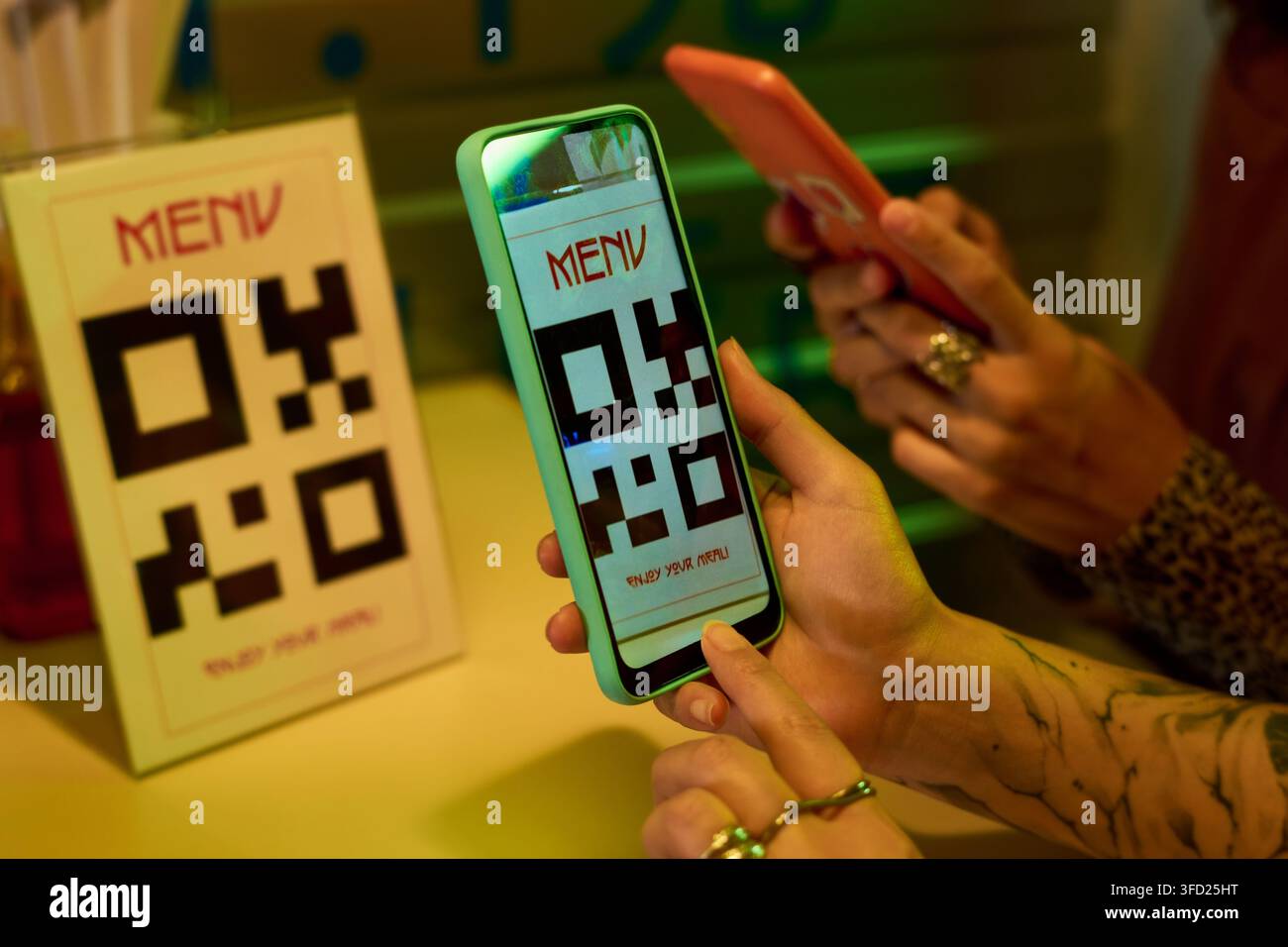 Giovani donne che scansionano il menu con codice QR utilizzando smartphone in un caffè in stile asiatico Foto Stock