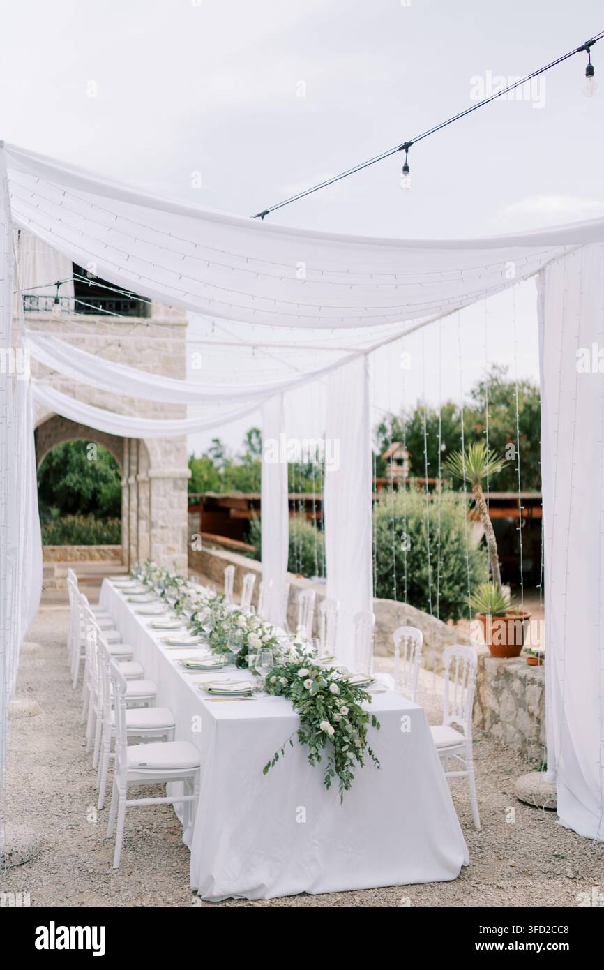 Elegante celebrazione serale sul fiume. Festa chic sul fiume con luci a drappeggio e decorazioni verdi Foto Stock