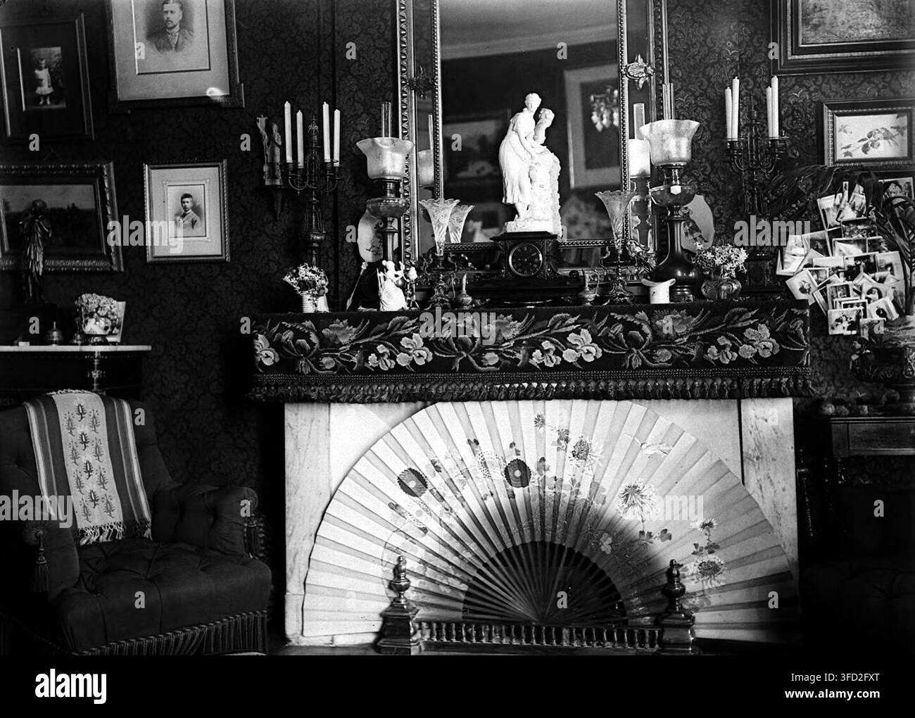 Un soggiorno in stile vittoriano con carta da parati ornata, un camino in marmo e vari oggetti, di Amélie Galup, una fotografa francese, tra il 1895 e il 1914. Foto Stock