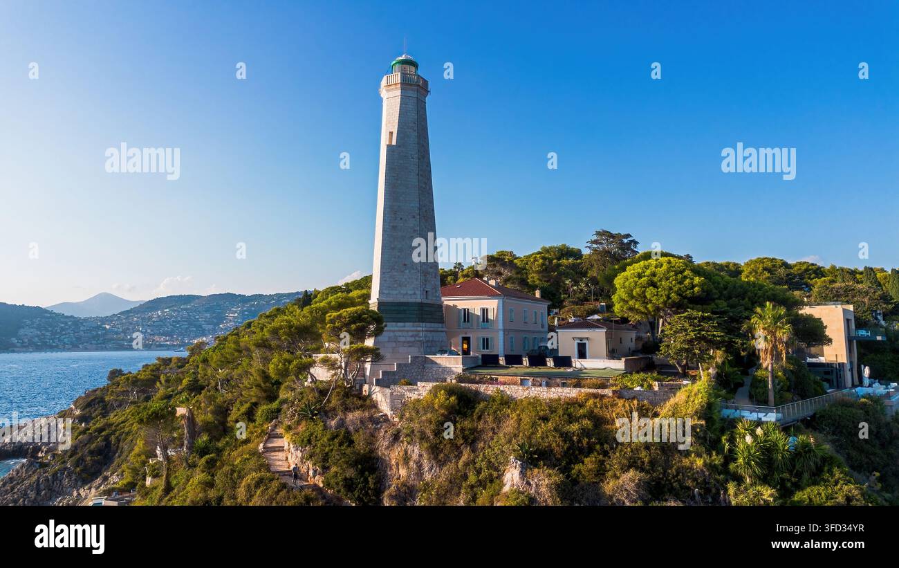 Vista aerea con drone del faro di Capo Ferrato circondato da boschi di pini e dal Mar Mediterraneo a Saint-Jean-Cap-Ferrat, Francia Foto Stock