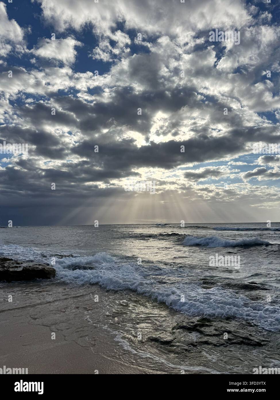 Raggi solari drammatici che si fanno strada tra le nuvole sopra l'oceano al Ho'okipa Beach Park, Maui, Hawaii Foto Stock