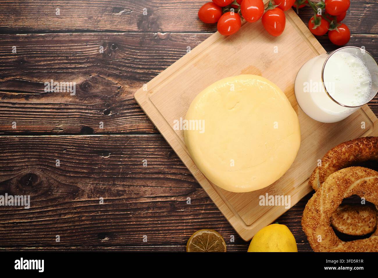 Formaggio, pomodori, latte e pane su tavola di legno Foto Stock