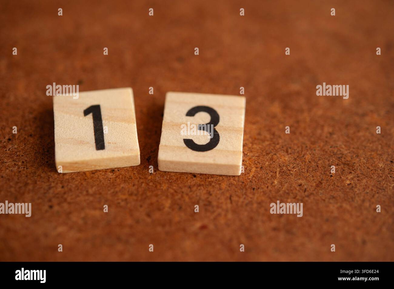 Piastrella di legno con il numero primo 13 su una superficie marrone rustica, concetto matematico con spazio di copia per l'educazione e la numerazione Foto Stock