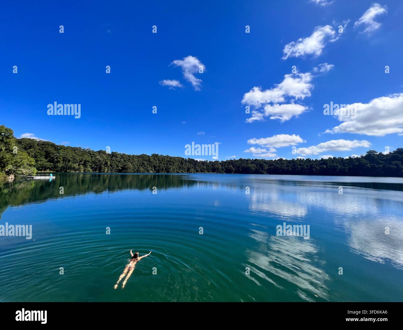 CAIRNS, QLD - 28 GIUGNO 2023: Veduta aerea di una donna australiana adulta che nuota nel lago Eacham, un lago popolare di origine vulcanica sull'altopiano di Atherton Foto Stock