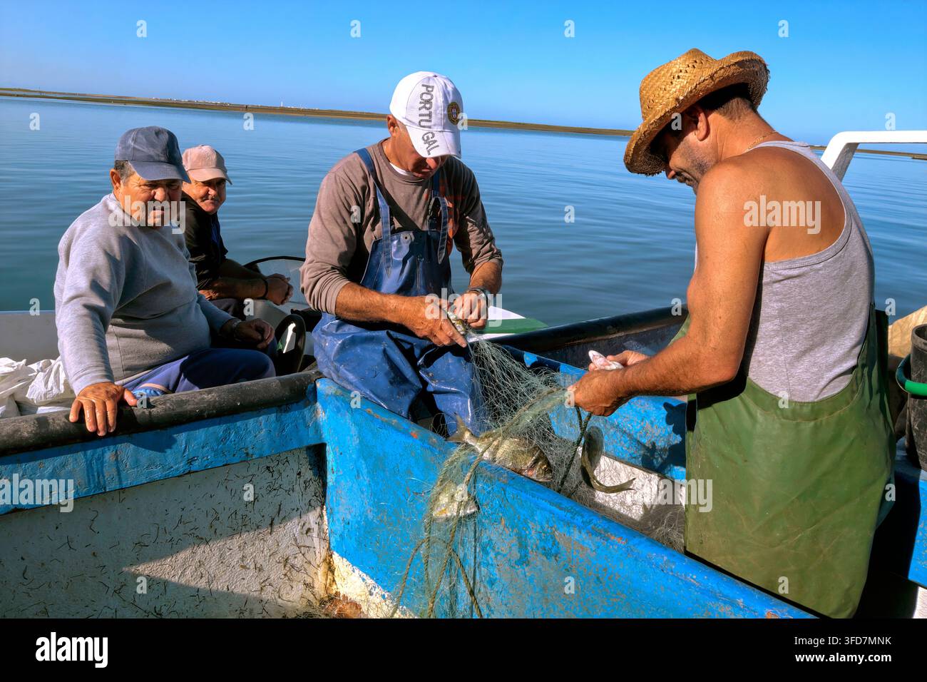 Pescatori portoghesi che rimuovono pesci dalla loro rete da pesca, Olhão, Sotavento Algarvio, Algarve, Portogallo, Europa Foto Stock