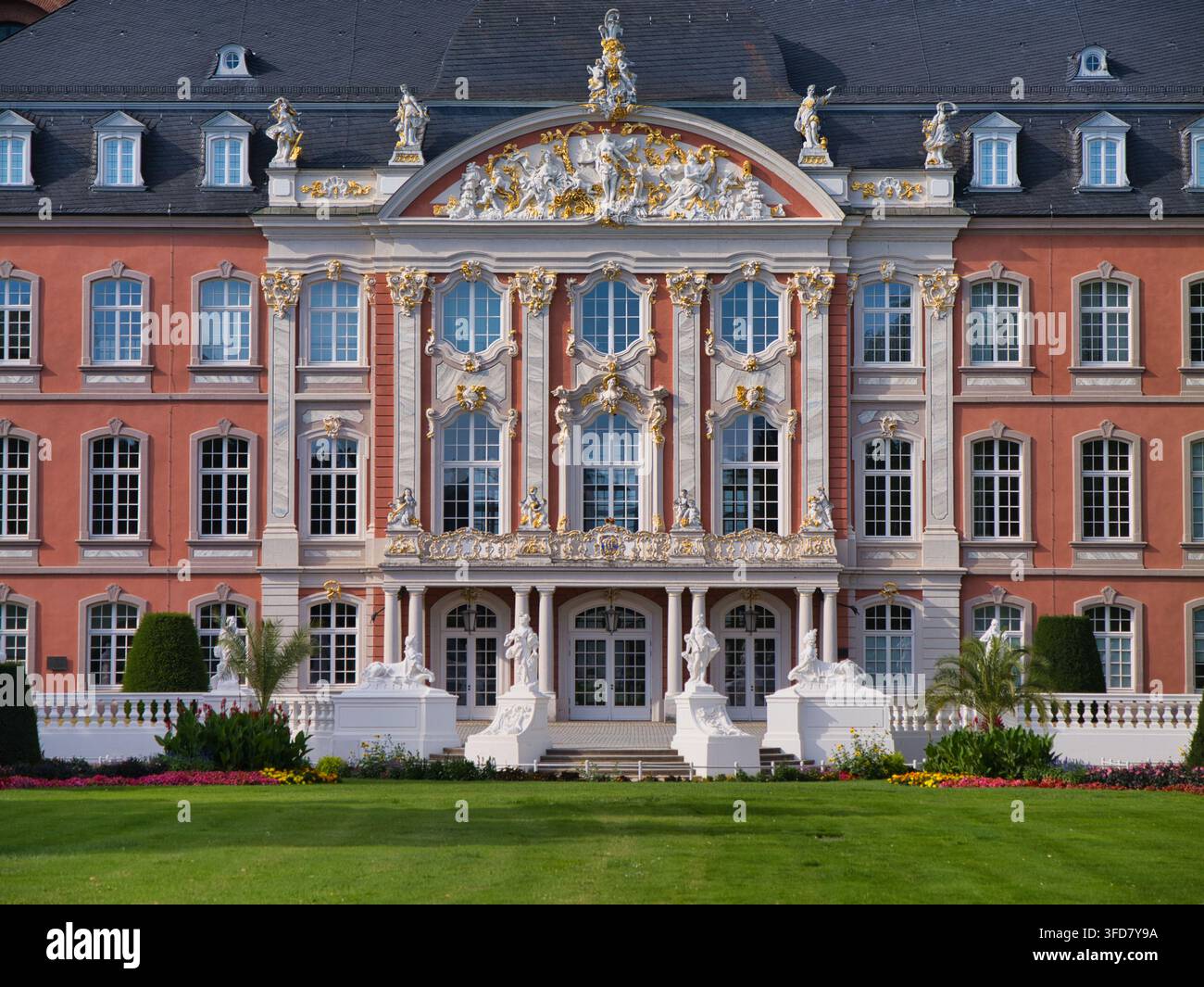 Trier, Germania – 10 lug 2026: Elegante facciata barocca rosa e bianca del Palazzo Elettorale a Trier, in Germania, con sculture dorate, giardini formali e grandi finestre Foto Stock