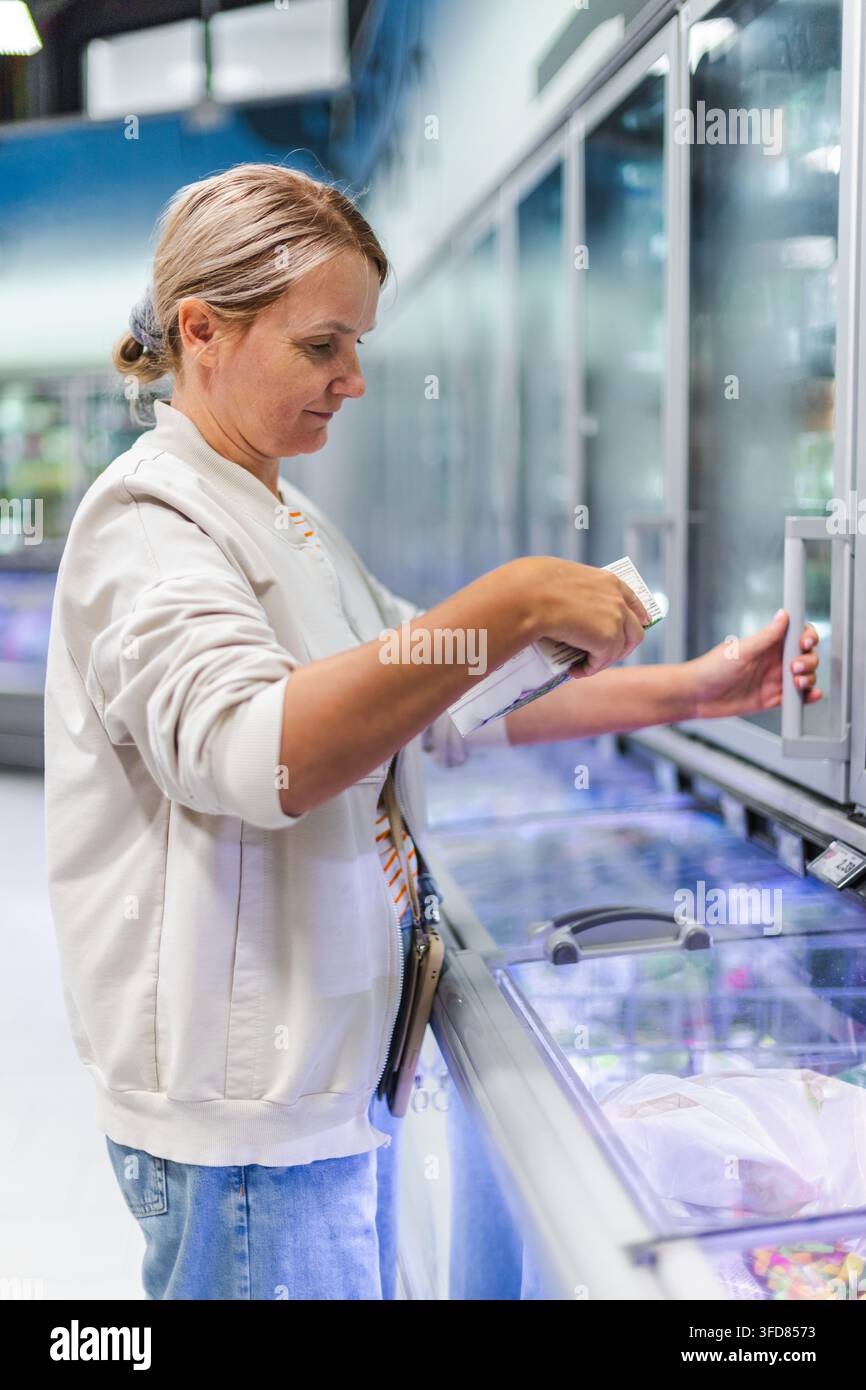 Donna che sceglie cibi confezionati dal congelatore del supermercato Foto Stock