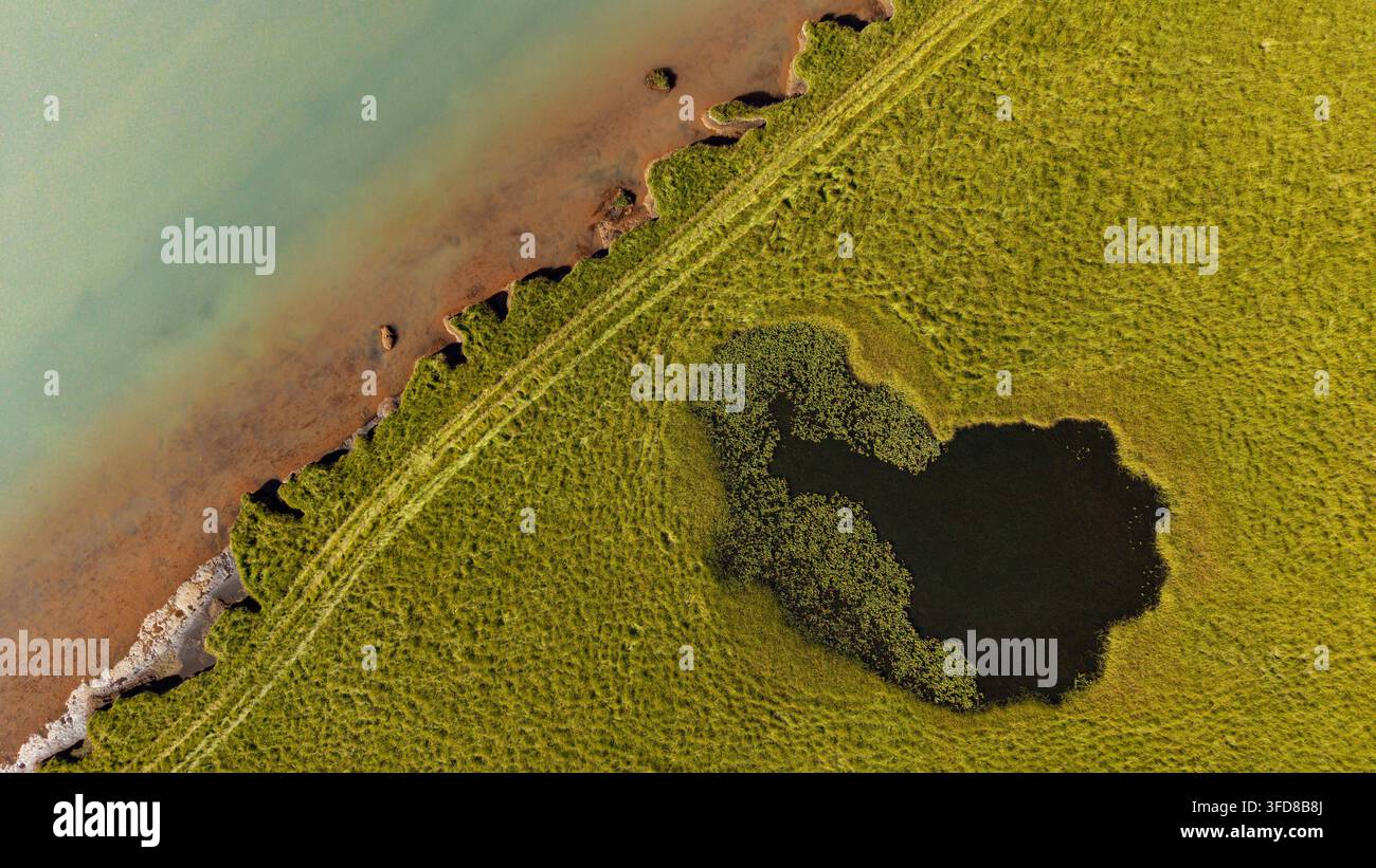 Vista aerea dall'alto delle pozze delle zone umide e dei modelli di rive dove le pianure basse di Flói incontrano il fiume Ölfusá nell'Islanda meridionale Foto Stock