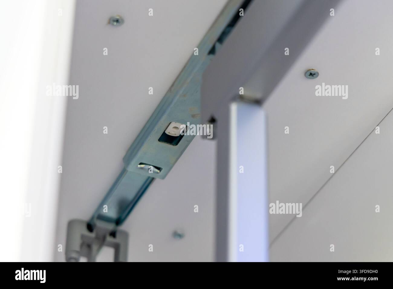Scatto dettagliato di un assemblaggio di guide per cassetti che mostra il binario metallico e le viti di fissaggio su uno sfondo bianco pulito Foto Stock