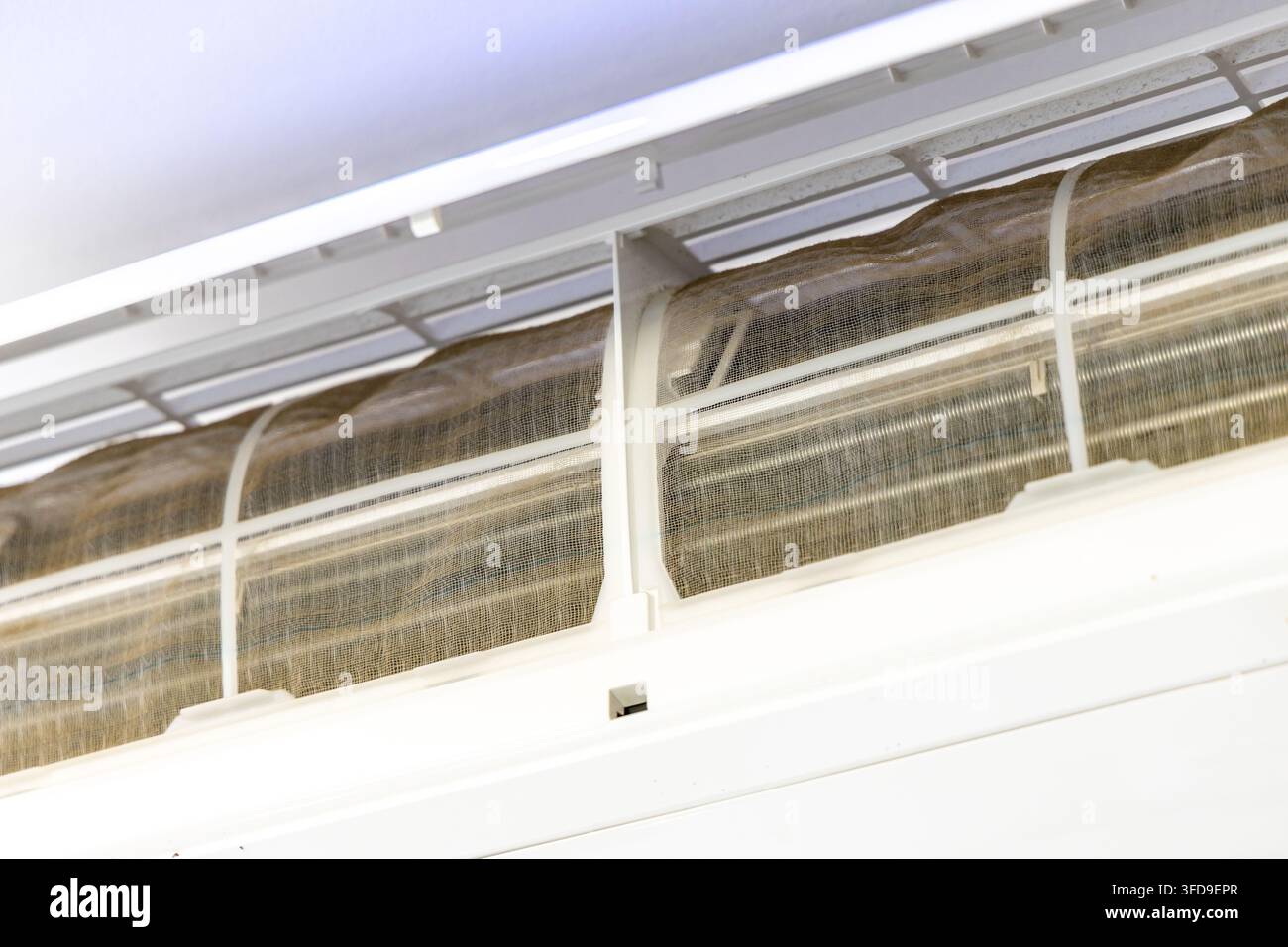 I componenti interni di un'unità di climatizzazione sono visibili, mostrando un filtro fortemente sporco che richiede pulizia per una prestazione ottimale Foto Stock