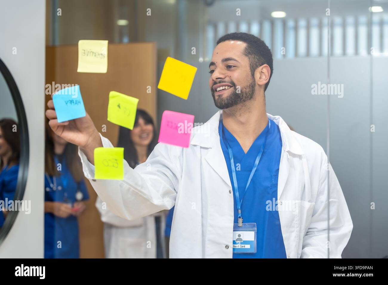 Professionisti medici che collaborano alla ricerca sulle cure dei pazienti utilizzando post-it Foto Stock