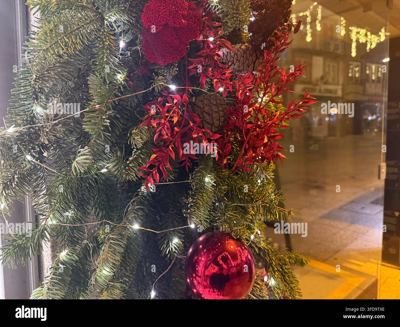 Ghirlanda natalizia con pallina rossa e luci di notte, riflessi urbani, concetto di vendita al dettaglio, decorazione per le feste, banner Foto Stock