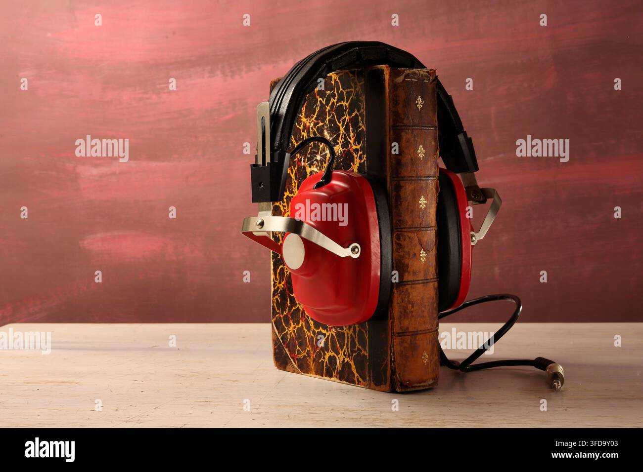 Concetto di audiolibri con una pila di libri e cuffie su uno sfondo naturale sfocato, spazio libero per la copia Foto Stock