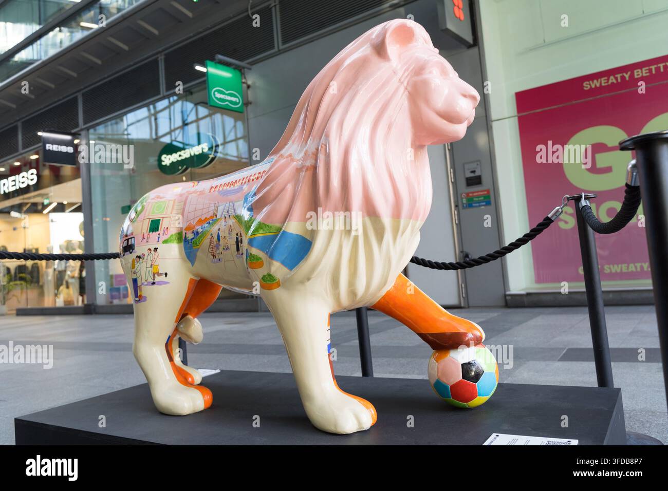 Una scultura di leone decorata dell'artista Sophia Hunter, parte del percorso di arte pubblica Pride in the Quarter, con un calcio ai suoi piedi, Londra, UK Foto Stock