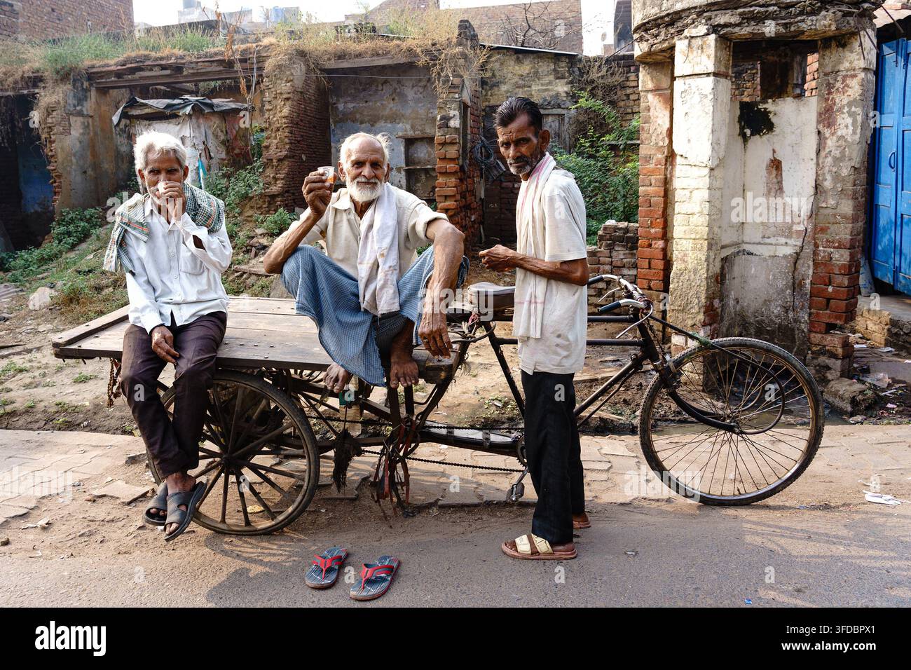 India. Uttar Pradesh. Agra. Tre uomini anziani condividono un tè intorno a un carretto // India. Uttar Pradesh. Agra. Three elderly men are sharing a cu Foto Stock