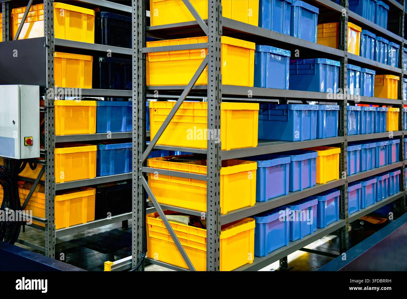 Scaffali metallici industriali pieni di contenitori di stoccaggio in plastica blu e gialli in un moderno magazzino logistico Foto Stock
