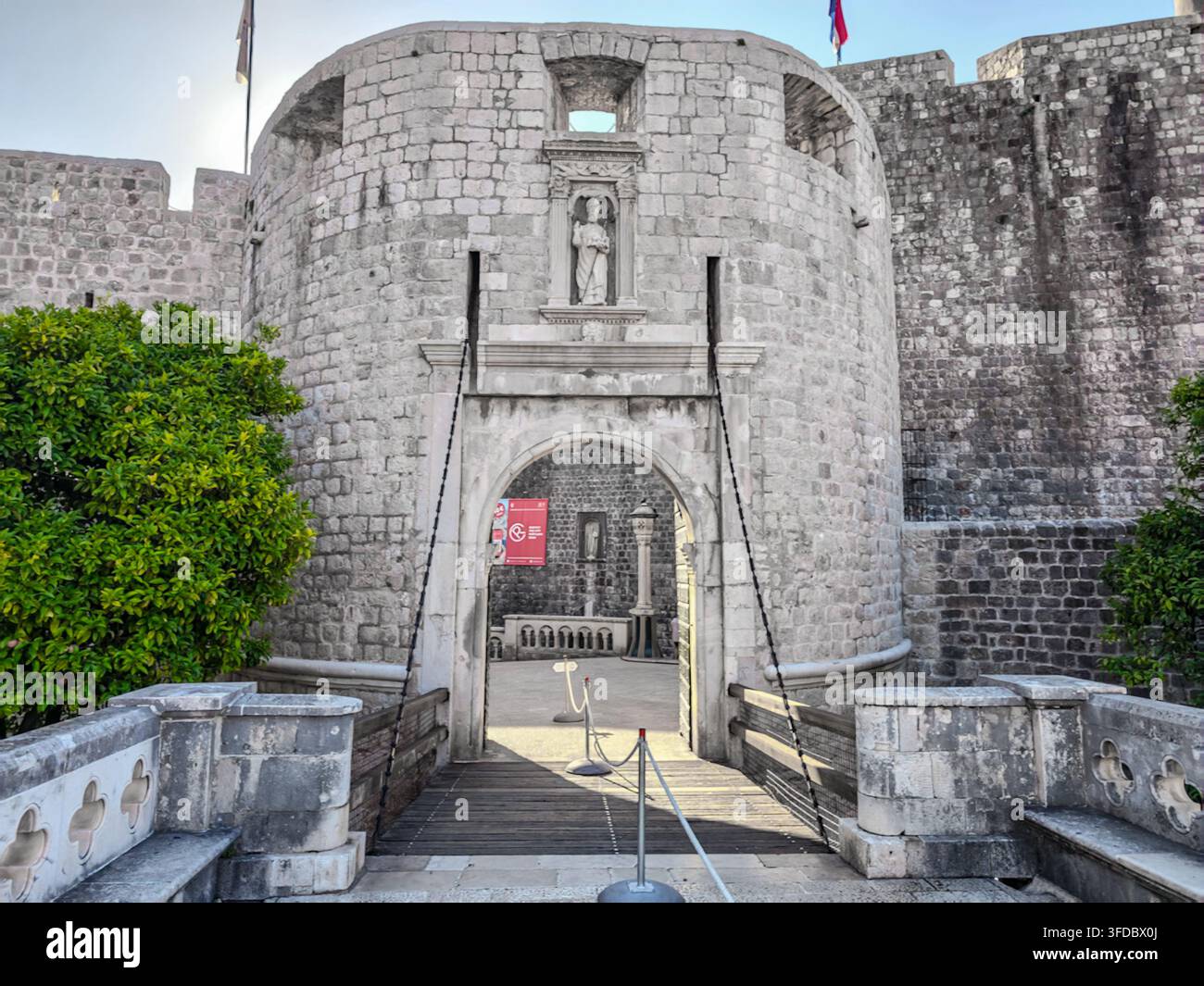 Una vista iconica dell'ingresso storico della Porta di Pile a Dubrovnik, Croazia, con antiche fortificazioni in pietra, dettagli architettonici e vegetazione rigogliosa - Immagine stock catturata con smartphone