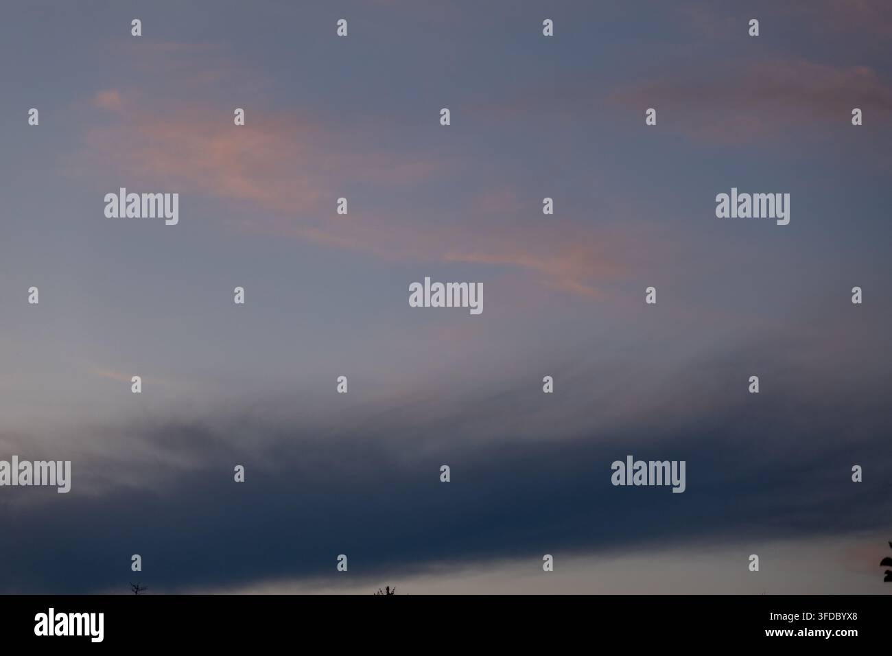 Cielo soffice al crepuscolo con una drammatica banda di nuvole blu e colori pastello Foto Stock