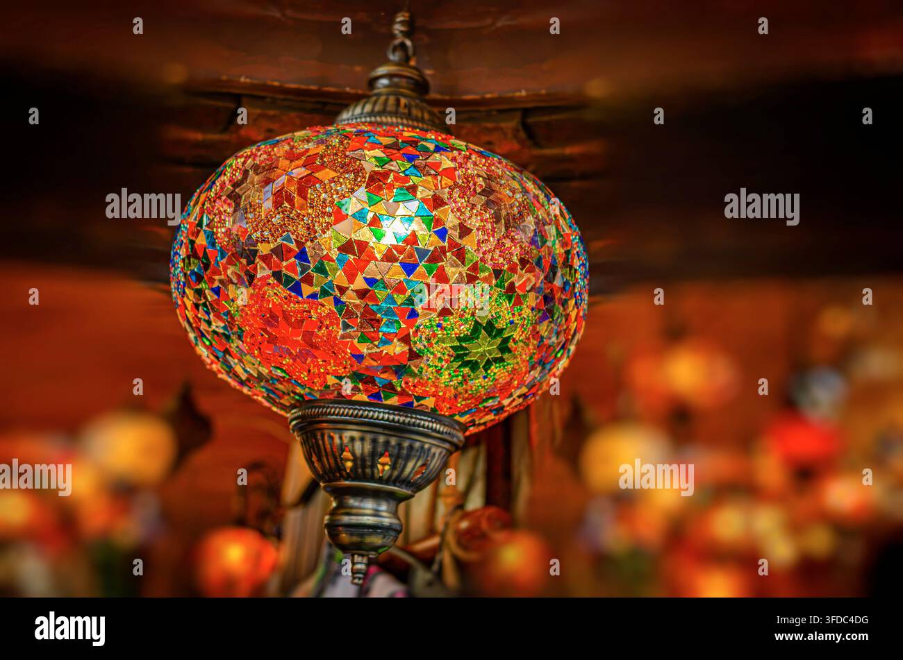 Una lanterna a mosaico fatta a mano brilla dolcemente su uno sfondo caldo e scarsamente illuminato. Foto Stock